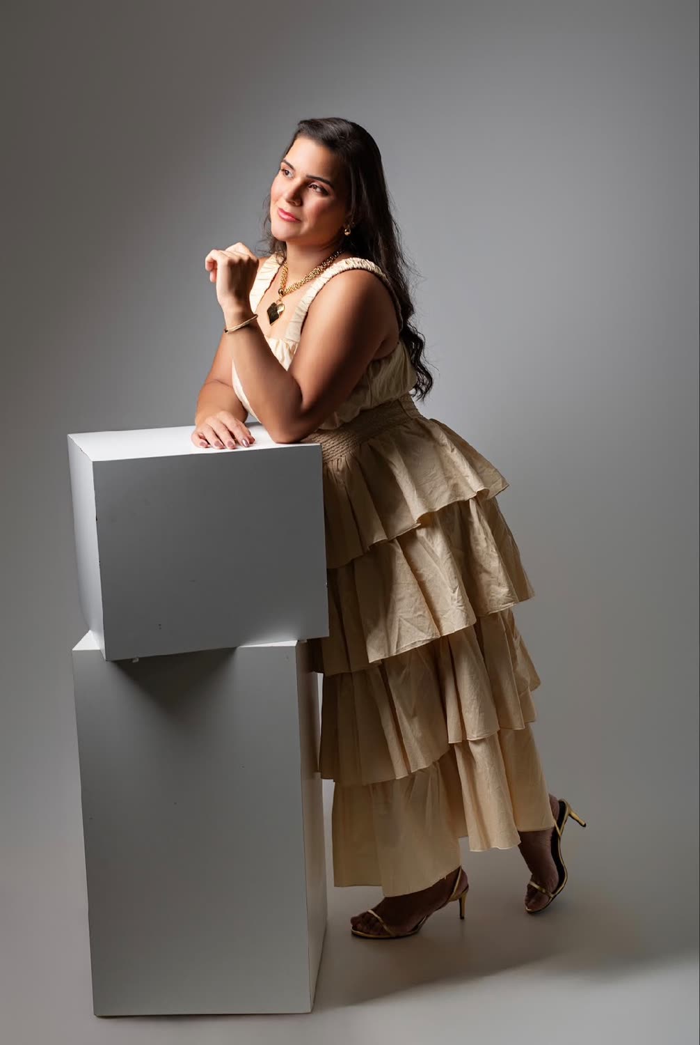 Bruna Patrícia em vestido de linho cru apoiada em um cubo, ensaio de estúdio